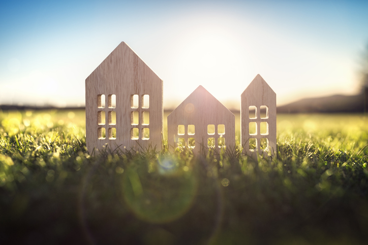 Ecological wood model house in empty field at sunset