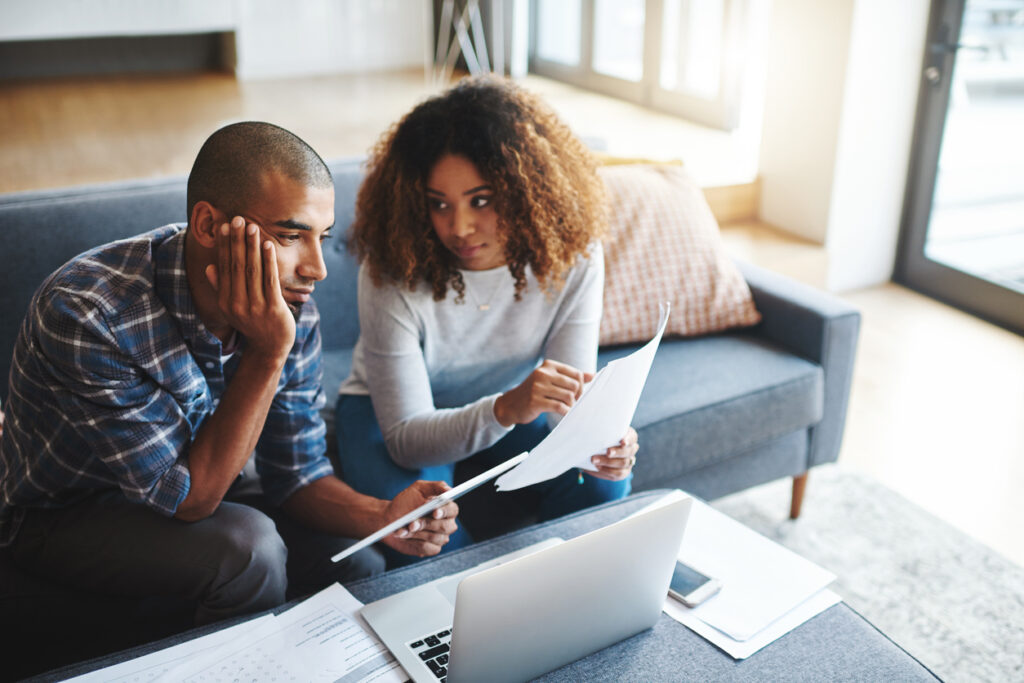 Cropped shot of a stressed young couple sitting together and using a laptop to go over their financial paperwork