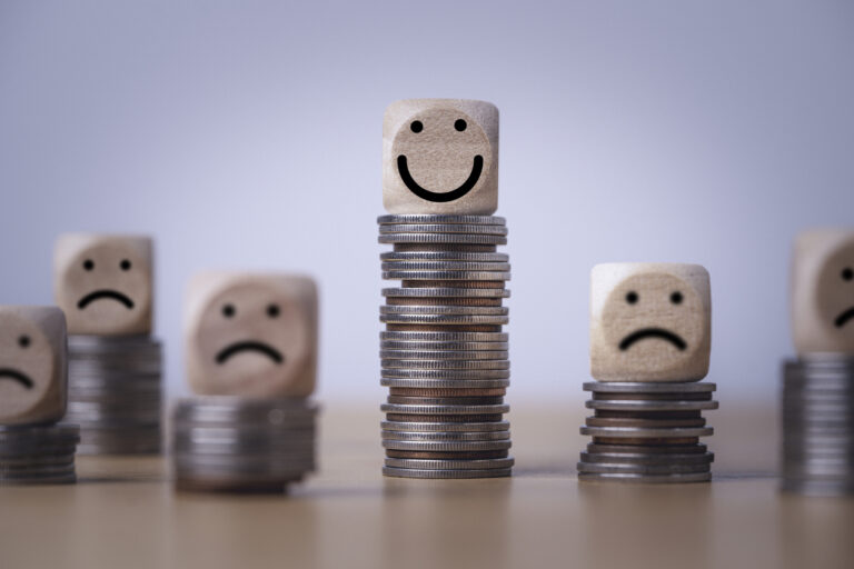 Multiple coin stacks with wooden blocks showing frowns for low stacks and a smile for tall stack of coins