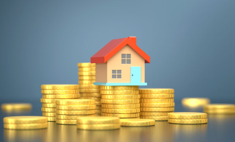 Toy house with red roof and light blue door sits on top of pile of gold coins.